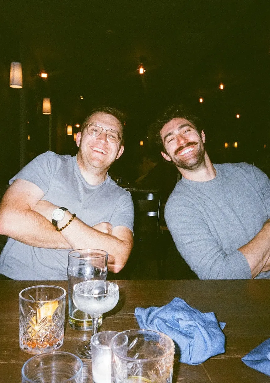 Two teammates at a table after work, mid-laugh.