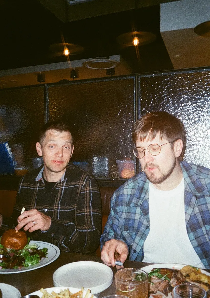 Two teammates in a restaurant booth over burgers and fries.