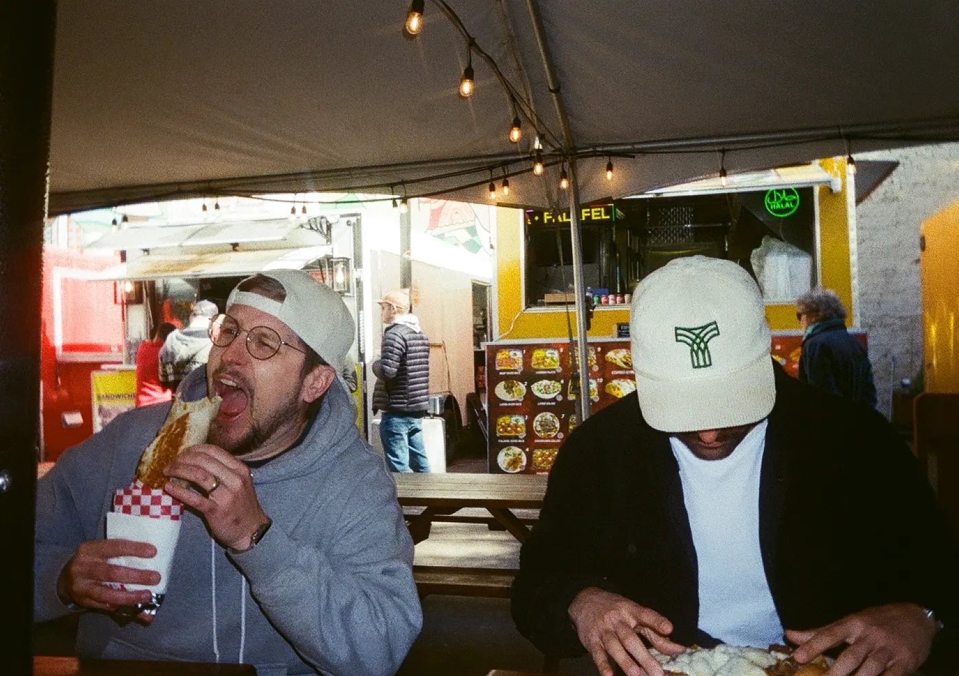 Two Thread teammates eating lunch at an outdoor food-cart pod under string lights.